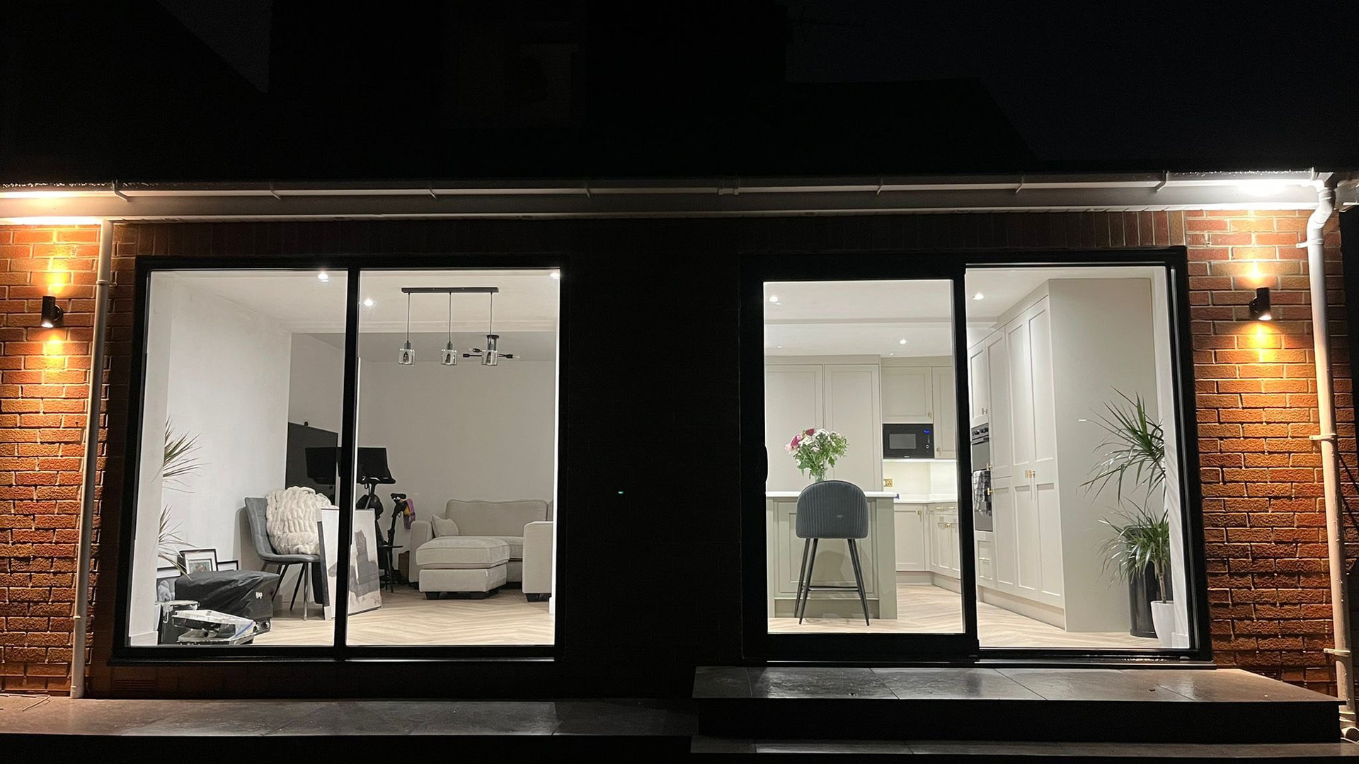 Lit kitchen through glass doors with exterior wall light — S.Yeoman Electrical Services